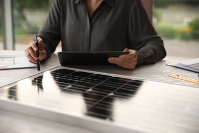 Woman working on project with solar panels at table in office, closeup