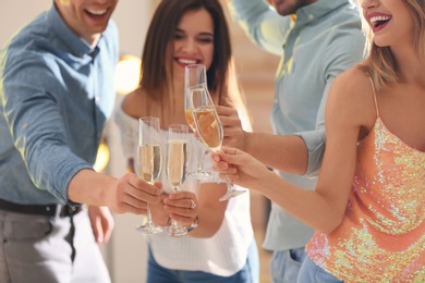 Friends clinking glasses with champagne at party indoors