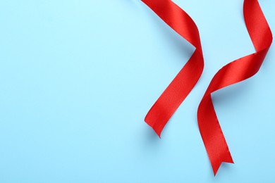 Photo of Beautiful red ribbons on light background, flat lay. Space for text