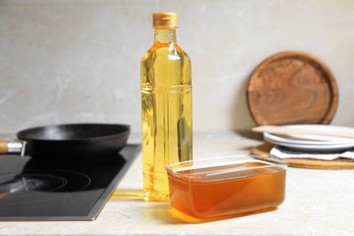 New and used cooking oil near stove on kitchen counter
