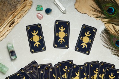 Tarot cards, peacock feathers, gemstones and old book on light table, flat lay. Reverse side