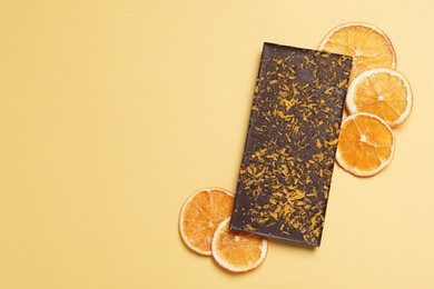 Chocolate bar with freeze dried orange on yellow background, flat lay. Space for text