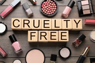 Flat lay composition with words Cruelty Free and different cosmetic products not tested on animals against wooden background
