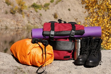 Set of camping equipment with sleeping bag on ground outdoors