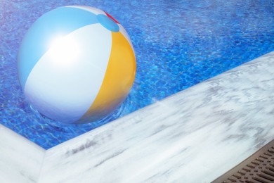 Inflatable beach ball floating in swimming pool 