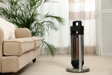 Modern electric halogen heater on floor in living room interior