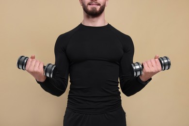 Photo of Man with exercising dumbbells on brown background, closeup