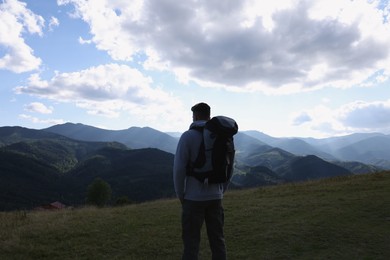 Tourist with backpack enjoying majestic mountain landscape, back view