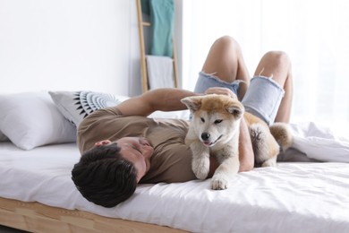 Image of Happy man with his cute Akita Inu puppy at home