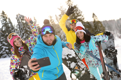 Group of friends taking selfie on snowy hill. Winter vacation