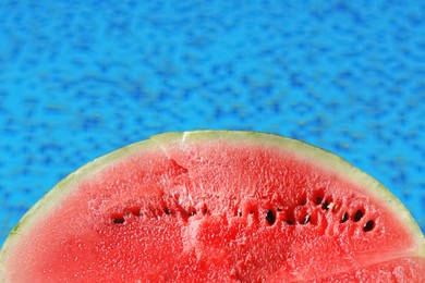 Photo of Half of fresh juicy watermelon near swimming pool outdoors, closeup. Space for text
