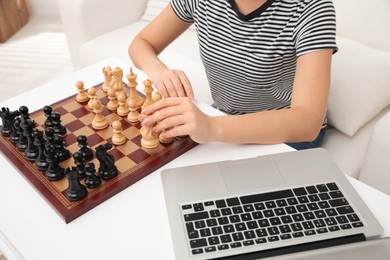 Woman playing chess with partner through online video chat at home, closeup