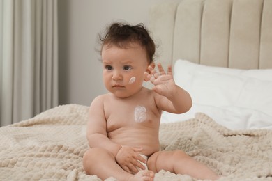 Cute little child with cream on skin in bedroom