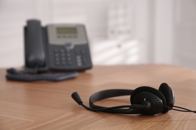Headset on wooden table indoors, space for text. Hotline service