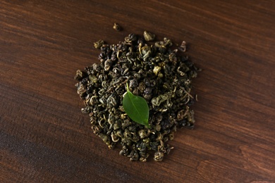 Heap of dried green tea leaves on wooden table, top view