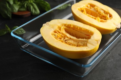 Halves of fresh spaghetti squash in baking dish on black table, closeup. Cooking at home