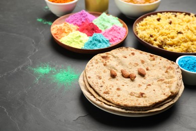 Traditional Indian food and color powders on black table. Holi festival celebration