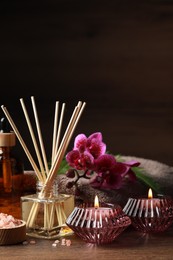 Photo of Beautiful spa composition with different care products and burning candles on wooden table