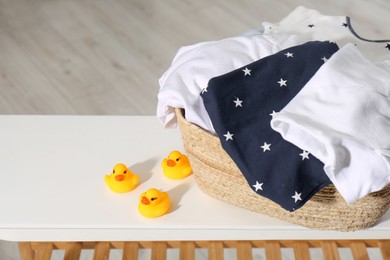 Photo of Laundry basket with baby clothes and rubber ducks on table in bathroom, closeup. Space for text