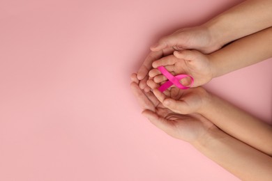 Woman and child holding pink ribbon on color background, top view with space for text. Breast cancer awareness