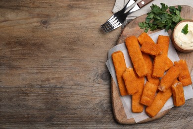 Tasty fresh fish fingers served on wooden table, flat lay. Space for text