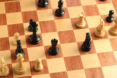 Wooden chessboard with game pieces, above view
