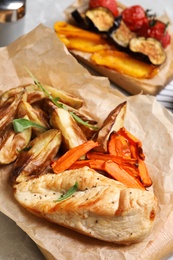 Photo of Delicious cooked chicken and vegetables on table, closeup. Healthy meals from air fryer