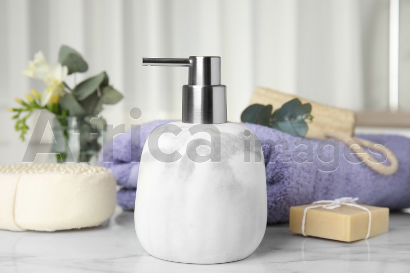 Soap dispenser and toiletries on white marble table