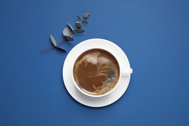 Classic black coffee and eucalyptus on blue background, top view. Color of the year 2020