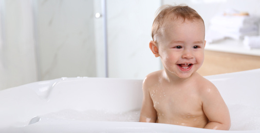 Cute little baby in bathtub at home, space for text. Banner design