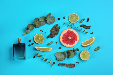 Photo of Beautiful flat lay composition with bottle of perfume, eucalyptus, tree bark and citrus fruits on blue background