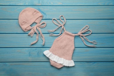 Set of cute baby knitwear for photoshoot on light blue wooden background, flat lay