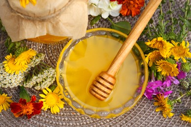 Delicious honey and dipper with different flowers on wicker mat, flat lay
