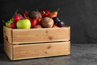 Wooden crate full of different vegetables and fruits on grey table. Harvesting time