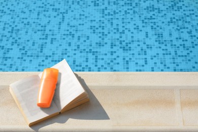 Photo of Open book and sunscreen on swimming pool edge, above view. Space for text