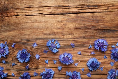 Beautiful blue cornflowers on wooden background, flat lay. Space for text