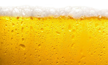 Glass of tasty cold beer with foam and condensation drops on white background, closeup