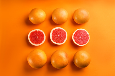 Cut and whole ripe grapefruits on orange background, flat lay