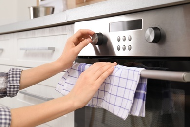 Photo of Young woman adjusting oven settings in kitchen, closeup