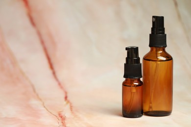 Bottles of organic cosmetic products on marbled background, space for text
