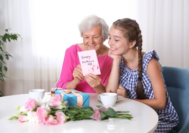 Preteen girl congratulating her granny at home. Happy Mother's Day