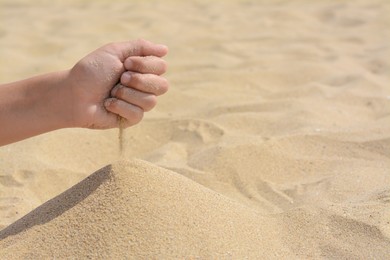 Child pouring sand from hand on beach, closeup with space for text. Fleeting time concept