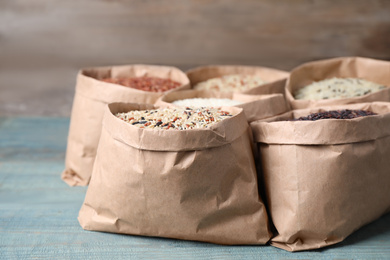 Brown and polished rice in paper bags on blue wooden table