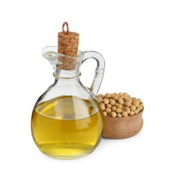 Glass jug of oil and soybeans on white background