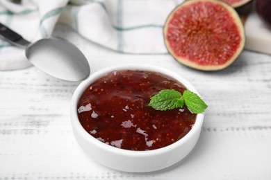 Photo of Tasty sweet fig jam and fruits on white wooden table, closeup