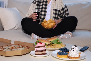 Overweight woman with chips, focus on unhealthy food