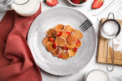 Delicious mini pancakes cereal with strawberries served on white marble table, flat lay