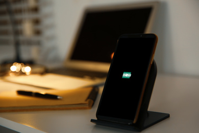 Mobile phone with wireless charger on table. Modern workplace accessory