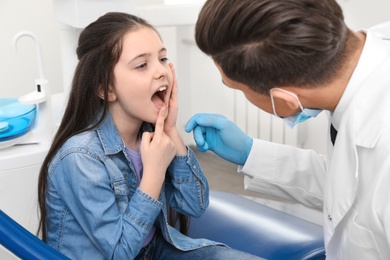 Professional dentist working with little girl in clinic