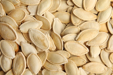 Raw unpeeled pumpkin seeds as background, top view